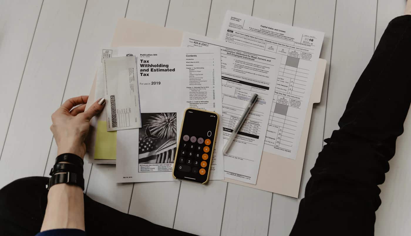 Calculadora e documentos financeiros sobre uma mesa, imagem contextual sobre pagamento de IRS.