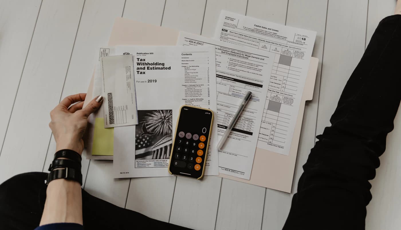 Calculadora e documentos financeiros sobre uma mesa, imagem contextual sobre pagamento de IRS.