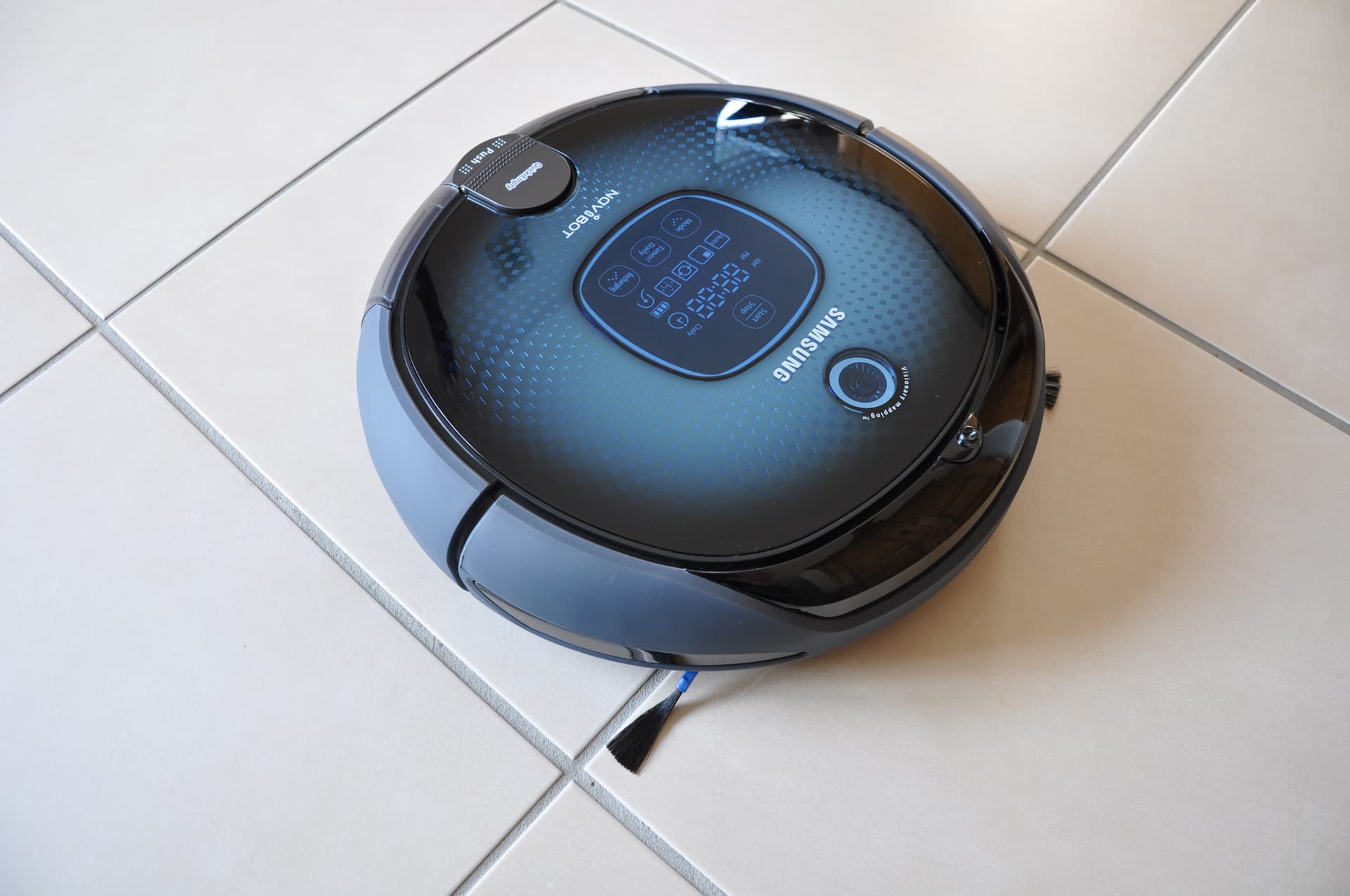 Robô aspirador Samsung fotografado sobre um piso claro